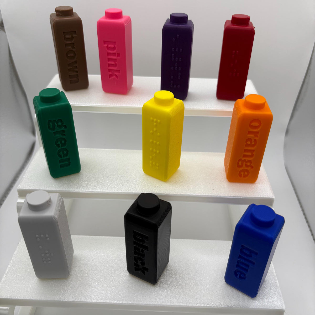 Braille toppers on Crayola Broad Line markers, each with a cap parked on the holder